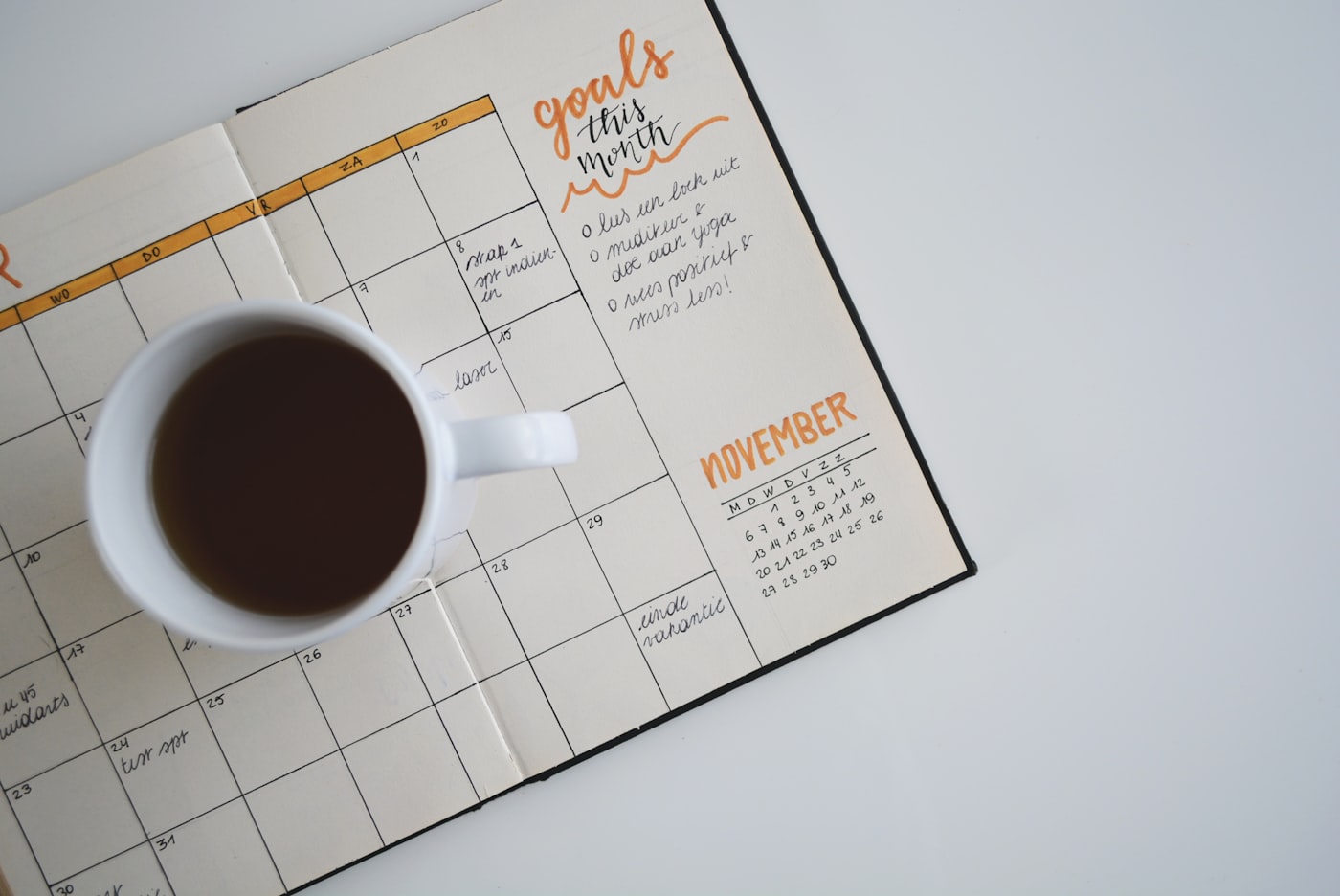 Weekly calendar planner on a desk with a coffee cup and notebook