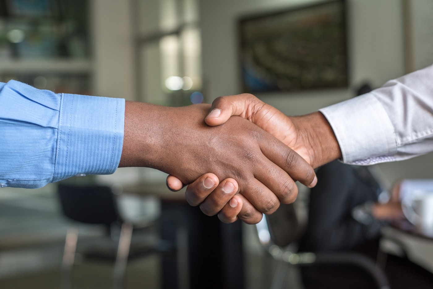 Two professionals shaking hands across a desk in a business meeting